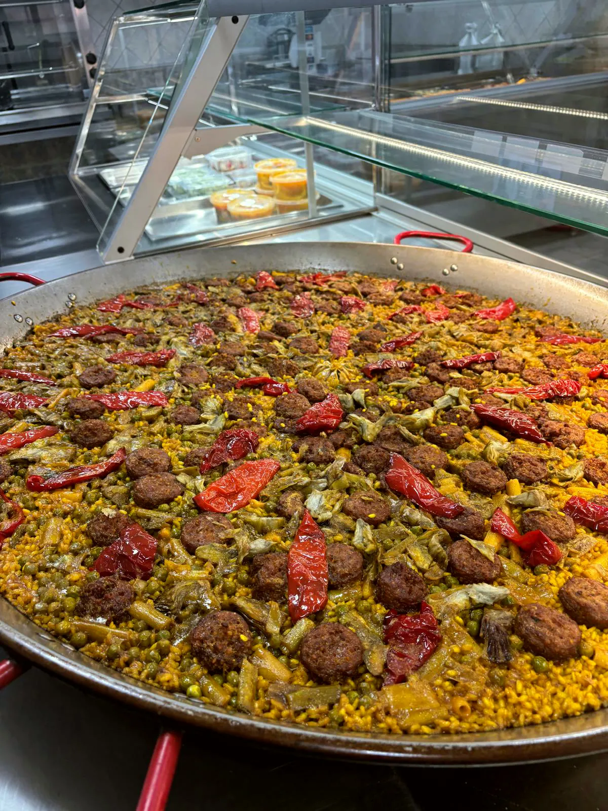 Paella de albóndigas con alcachofas, judías y pimiento rojo